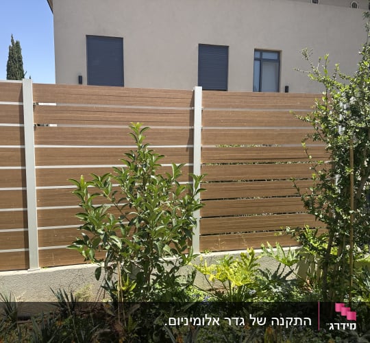 גדר אלומיניום חומה עם צמחייה ירוקה